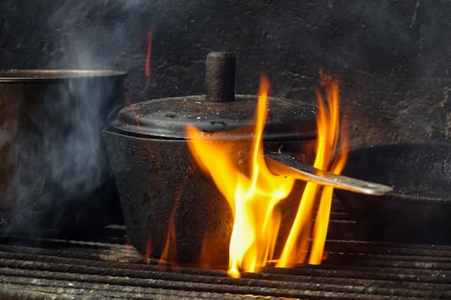 Ein Fettbrand in einer Pfanne wird mit einem Fettbrandlöscher gelöscht.