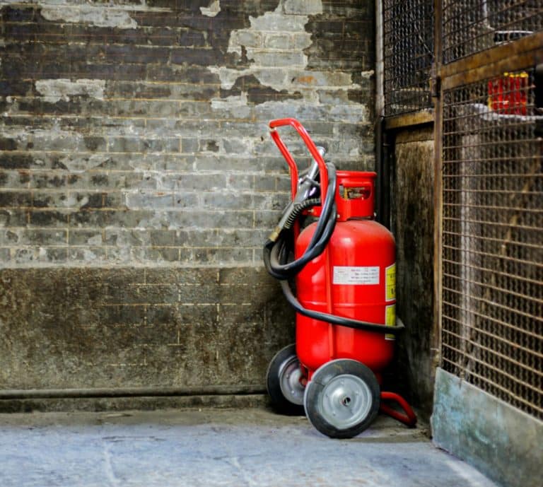Feuerlöscher auf Rädern an einer Industrie-Wand.